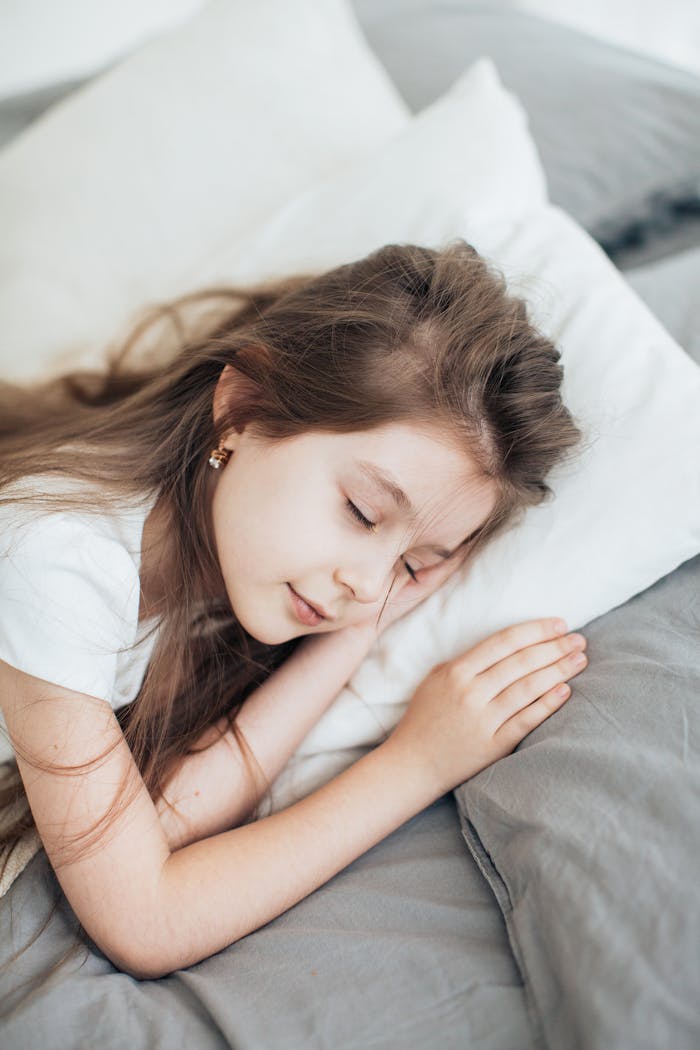 Young girl peacefully sleeping in a cozy bedroom setting, capturing childhood serenity.
