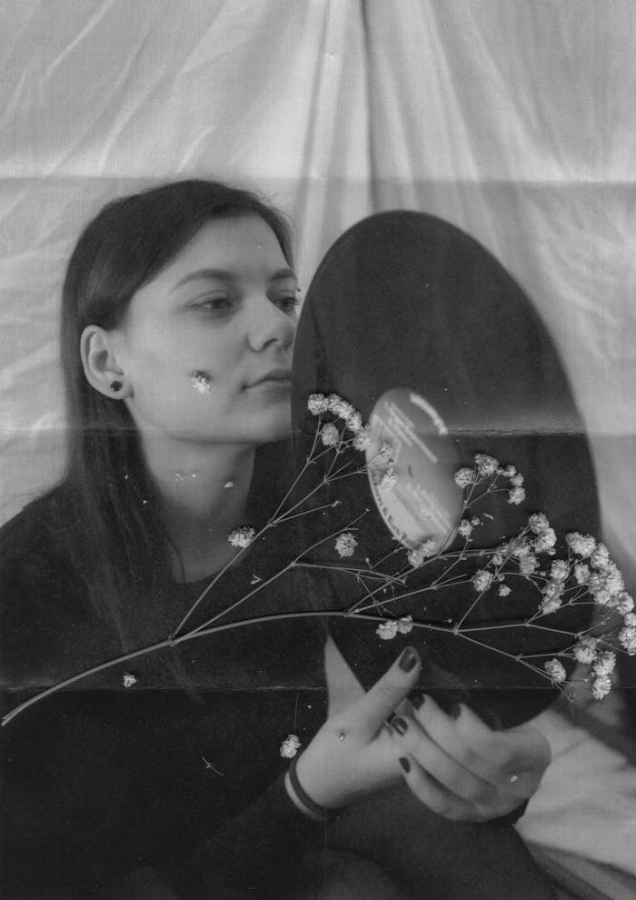 Black and white of young female holding vinyl under dried twig with flowers